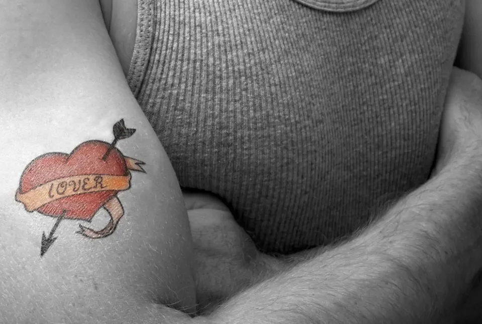 alt="cuore rosso tatuato su un braccio muscoloso di uomo"